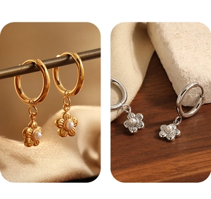 Macro shot of gold and silver flower earrings with pearls on natural stone background