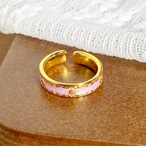 Gros plan sur une bague vintage en or avec émail rose et détails en filigrane ajouré