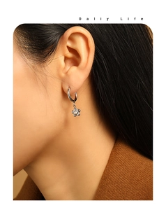 Detailed close-up of a silver flower drop earring with a pearl center on a model