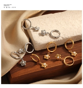 Detail of elegant gold and silver flower hoop earrings with pearls on silk background