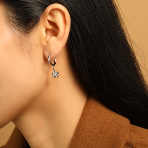 Elegant silver flower hoop earrings with white pearl bead, worn by model in warm lighting