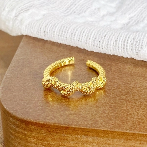 Détail d'une bague vintage en émail doré avec texture tissée et design ouvert