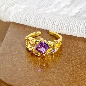 Vue détaillée d'une bague vintage dorée avec zircon violet et texture de lave