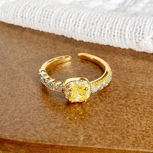 Détail d'une bague vintage en or avec pierre jaune et sertissage de cristaux