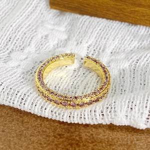 Gros plan d'une bague dorée vintage avec doubles rangées de zircons violets et design ouvert