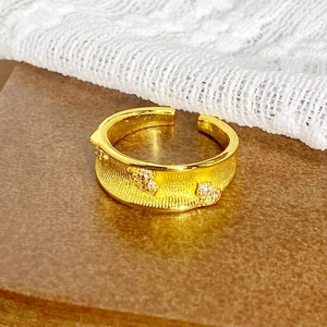 Détail macro d'une bague vintage dorée avec texture brossée et incrustation de zircon
