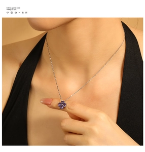 Dettaglio della collana a quadrifoglio dorata con pietra a cuore viola indossata
