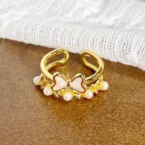 Détail de la bague vintage dorée avec noeud en émail rose et perles nacrées
