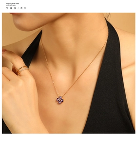 Dettaglio di una collana con ciondolo a quadrifoglio viola e set di anelli dorati