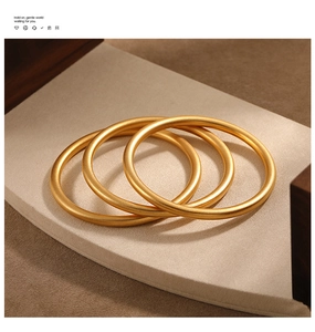 Detailed close-up of matte 24K gold-plated bangles showing the 999 hallmark engraving