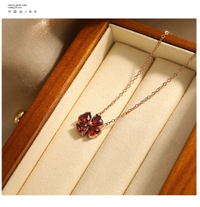 Dettaglio macro della collana in oro rosa con ciondolo quadrifoglio e gemme rosse