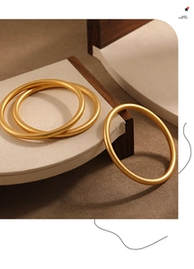 Detail of three matte gold-plated bangles with a refined frosted finish and 24K gold luster
