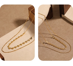 Vue détaillée de colliers double couche en or PVD avec pendentifs cœur et fleurs gravés