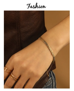 Detail of a PVD gold plated snake bone bracelet with adjustable extension on model's wrist