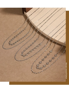 Vue détaillée de colliers argentés à plusieurs rangs avec breloques cœur et trèfle sur socle