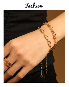Detail of engraved oval link gold bracelet and grooved ring set on model's wrist