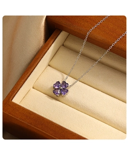 Dettaglio della collana a quadrifoglio con zirconi viola a cuore in una scatola di legno