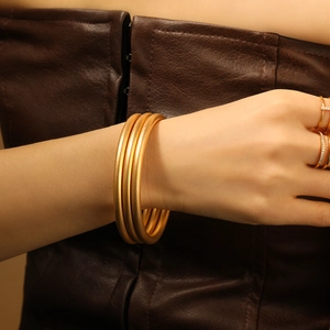 Three-piece set of matte gold bangle bracelets with a minimalist frosted finish for women