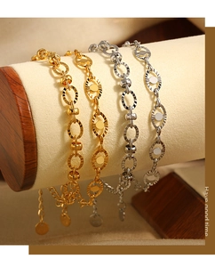 Detailed macro of gold and silver steel chain bracelets with embossed oval links and logo tags