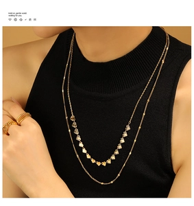 Vue détaillée d'un collier double épaisseur doré avec des pendentifs en forme de cœur