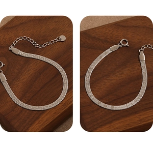 Detail view of a silver herringbone snake chain bracelet with adjustable clasp extension