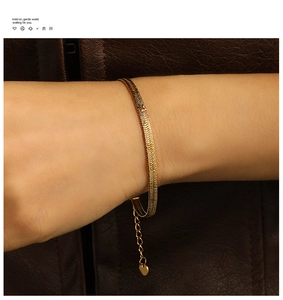 Close-up of gold snake bone chain bracelet with heart charm and delicate fish-scale texture