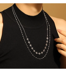 Détail du collier argenté à double épaisseur avec pendentifs trèfles évidés sur modèle