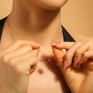 Elegante collana a quadrifoglio in titanio placcato oro con quattro pietre rosse a cuore