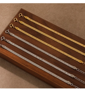Detailed close-up of gold and silver flat snake bone chain bracelets with spring clasps