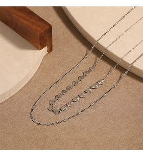 Vue détaillée d'un collier double épaisseur argenté avec pendentifs cœurs gravés