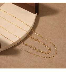 Détail du collier doré double épaisseur avec motifs de trèfles et finitions texturées fines