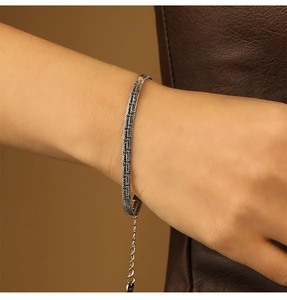 Detail view of a fine silver snake bone chain bracelet with S925 engraved tag on model