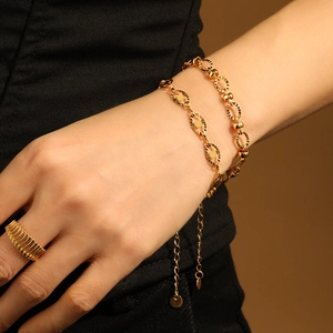 Gold-plated oval link bracelet and wide ring jewelry set worn on model's hand
