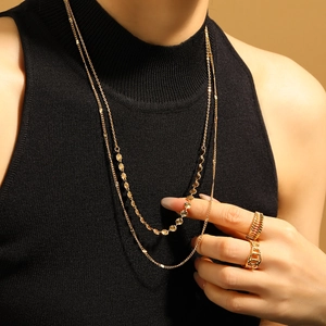 Collier doré à plusieurs rangs avec breloques rondes et bagues spirales sur modèle