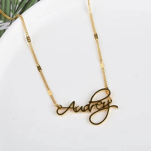 Elegant gold necklace with Audrey name pendant on white porcelain background