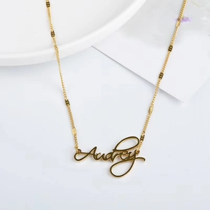 Custom 18K gold Audrey name pendant necklace with sequin chain on white ceramic tray