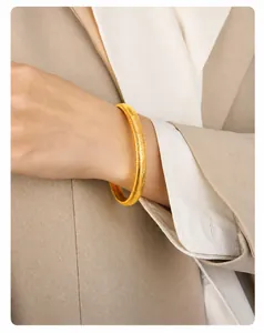 Detailed close-up of a gold-plated snake bone texture bracelet on a woman's wrist