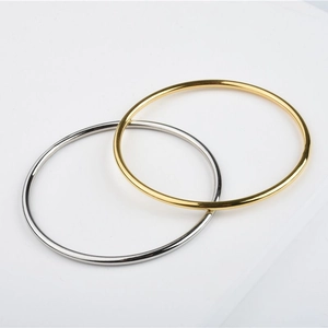 Detail shot of minimal polished 24K gold and silver titanium steel bangles on white
