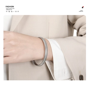 Detailed view of silver snake-pattern spring cuff bracelet worn with modern outfit