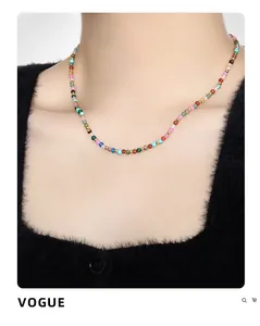 Bunte Perlenkette im Boho-Stil mit goldenen Details an einem Model vor schwarzem Hintergrund