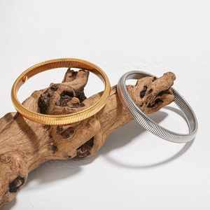 Elegant gold and silver spiral snake bone elastic bracelet set on wooden branch stand