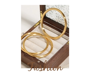 Detailed view of three 24k gold plated brushed titanium steel bangles in a jewelry box