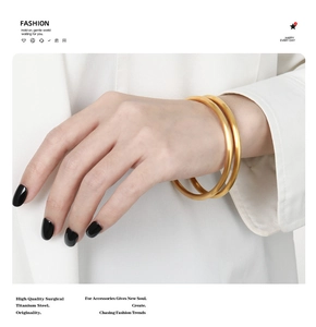 Detail view of two surgical titanium steel gold bangles with matte brushed finish on wrist