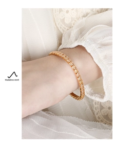 Detailed macro view of a gold-plated stainless steel tennis bracelet with zircon stones