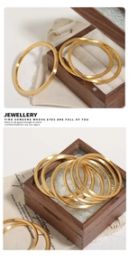 Macro shot of 24k gold plated stainless steel bangles set on a linen and wood display