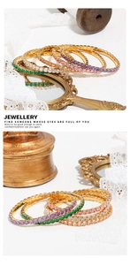Detail of five colorful zircon tennis bracelets with gold finish on a vintage background