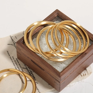 Minimalist stackable matte 24k gold plated titanium steel bangles on wooden box