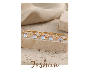 Set de cinco anillos trenzados dorados con piedras lunares sobre soporte de piedra
