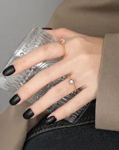 Detalle de anillos apilados de oro con piedra lunar en la mano sosteniendo una copa
