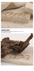 Detalle de anillos de acero de titanio dorado trenzado con piedras de luna irisadas